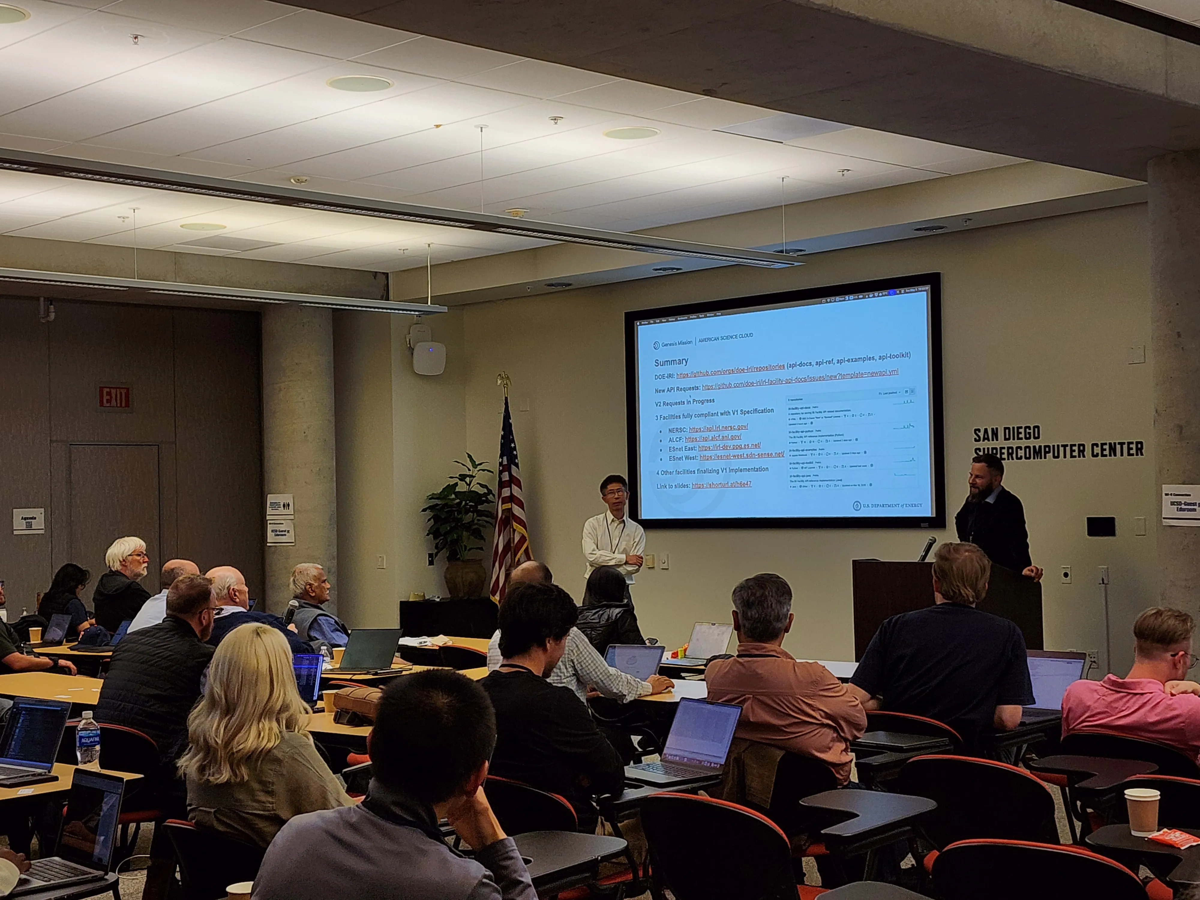 Justas and Xi closing the session on the AmSC summary slide — links to docs, API reference, examples and spec